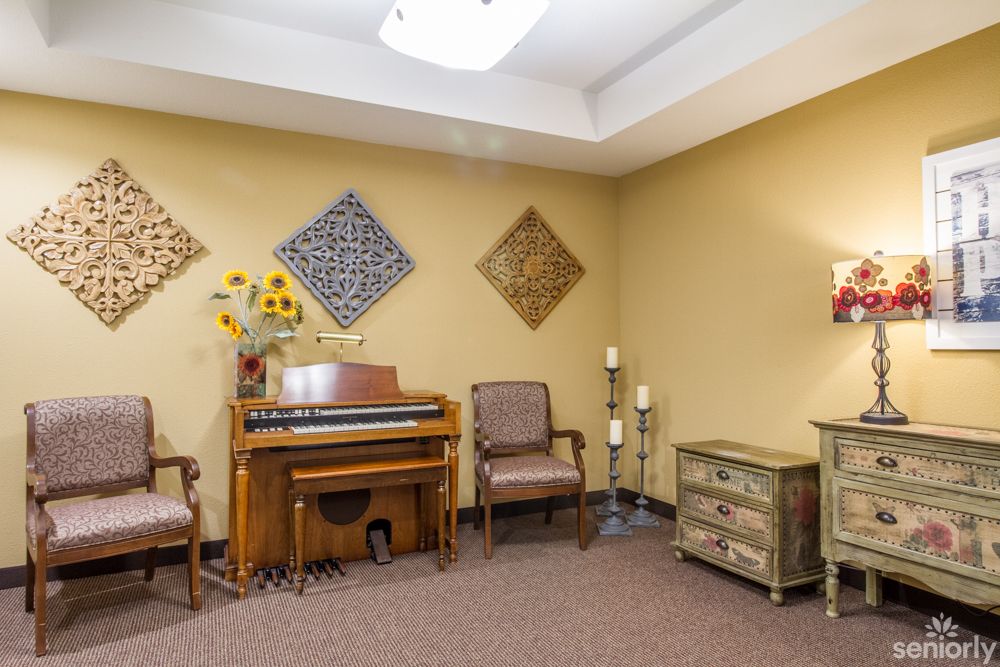 A cozy room featuring a piano, chairs, and decorative elements on the walls.