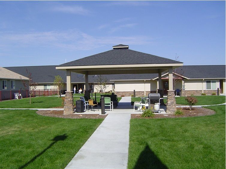 A gazebo with seating and a pathway in a well-maintained outdoor garden area.