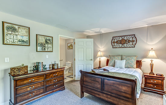 A cozy bedroom with a wooden bed, matching dresser, and tasteful decorations.