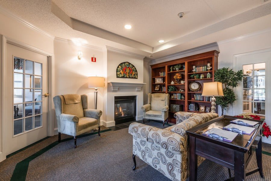 A cozy living room with a fireplace and comfortable seating, featuring elegant decor and a well-stocked bookshelf.