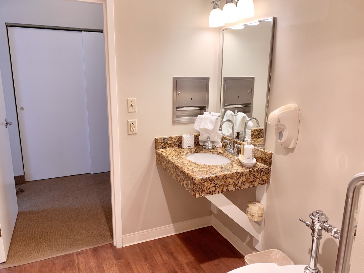 A clean and modern bathroom with a granite countertop and wall-mounted sink.