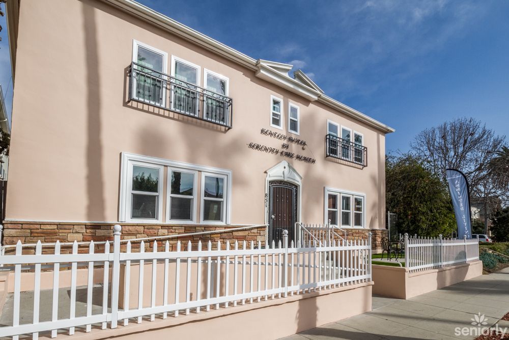 A residential two-story building with white railings and multiple windows.