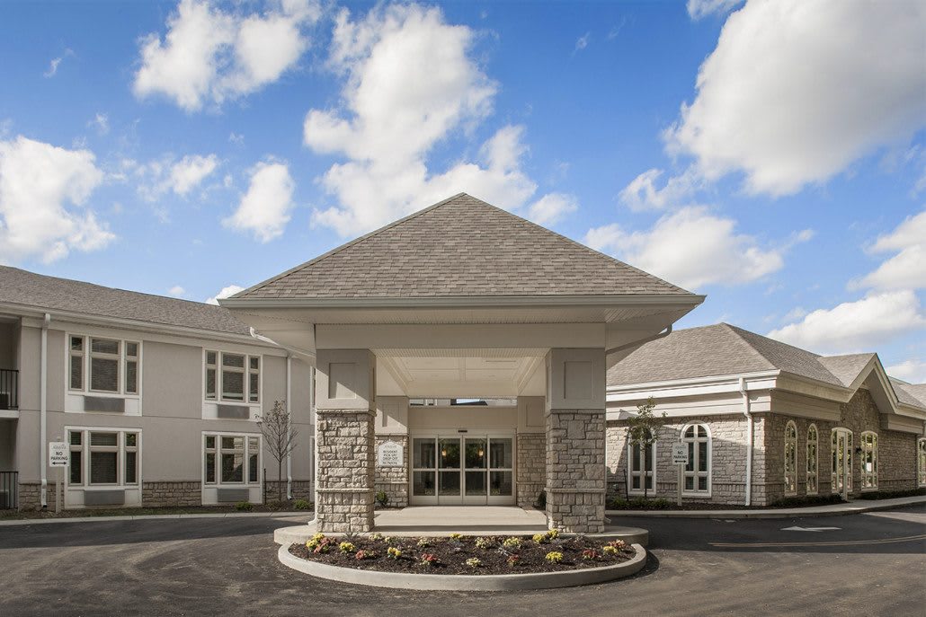 A modern building entrance with a triangular roof against a partly cloudy sky.