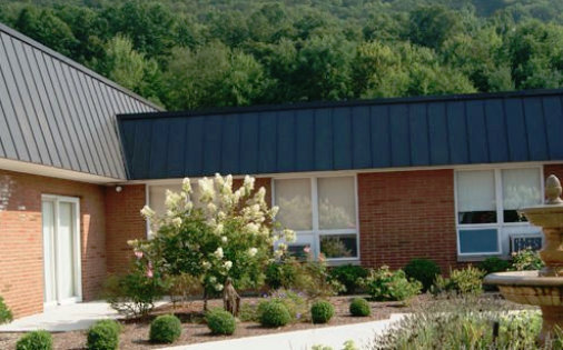 A serene view of a building surrounded by lush greenery and blooming flowers.