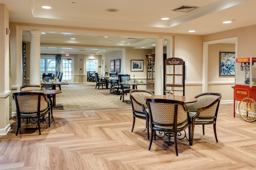 A cozy dining area with wooden flooring and neatly arranged tables and chairs.