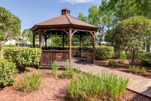 A charming wooden gazebo surrounded by lush greenery in a well-maintained garden.