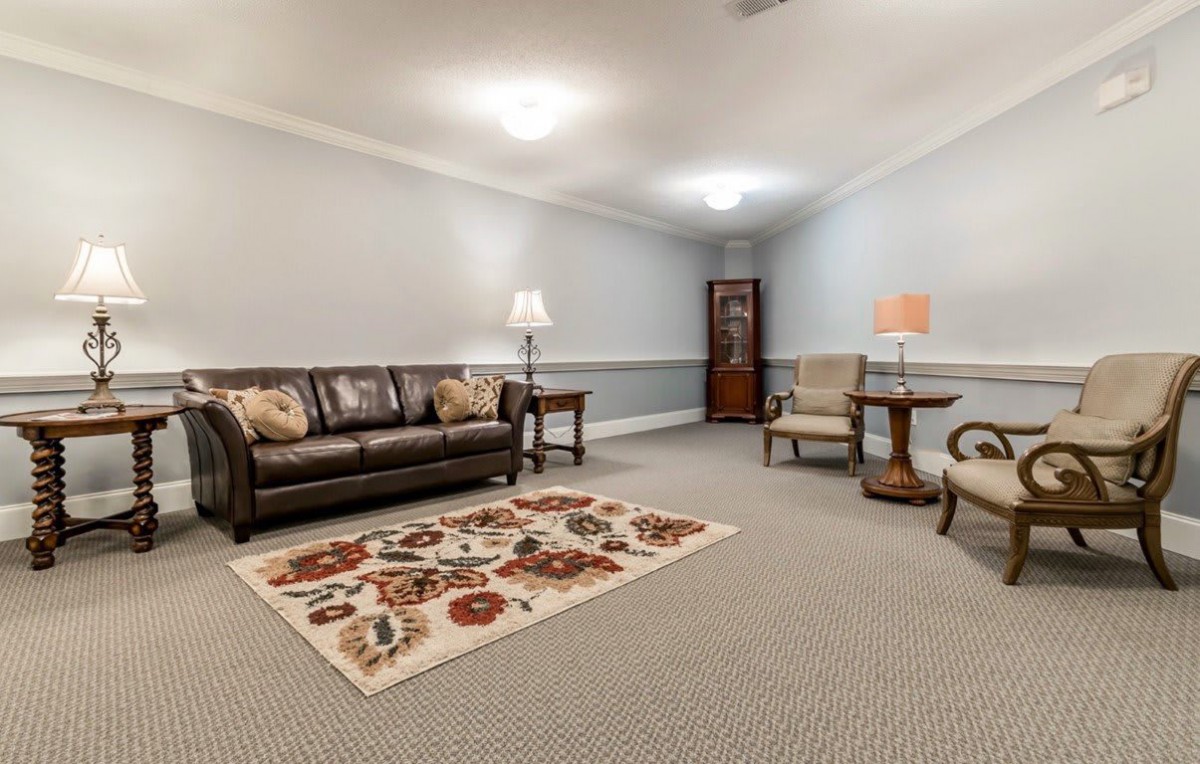 A cozy living room with a sofa, chairs, and a colorful carpet.