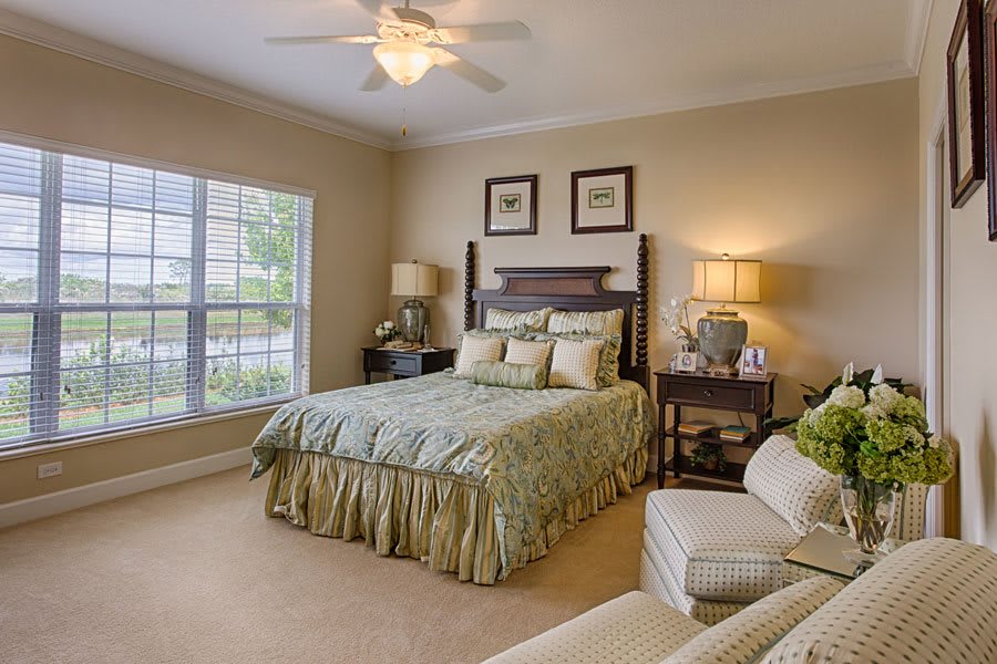 A cozy and well-decorated bedroom with a large window and comfortable furnishings.
