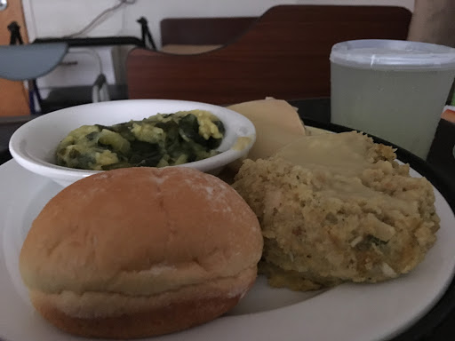 A hearty meal featuring a bread roll, cooked greens, and a grain dish.