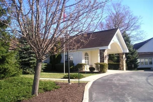 A suburban house with a driveway and surrounding trees.
