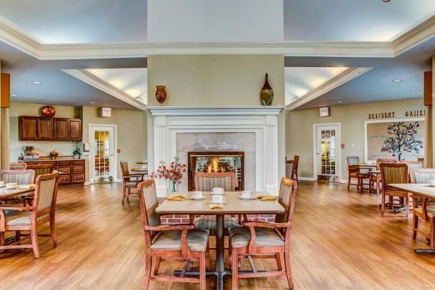 A cozy dining room with a central fireplace and neatly arranged tables and chairs.