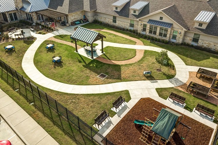 Aerial view of a playground with pathways, benches, and play equipment surrounded by buildings.