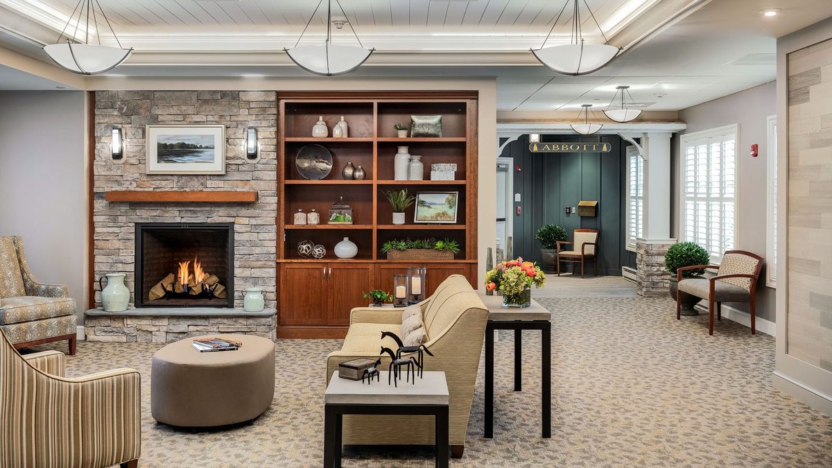 A cozy living room with a modern fireplace, bookshelf, and comfortable seating.