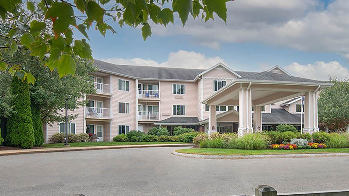 A three-story residential building with a landscaped entrance and surrounding trees.