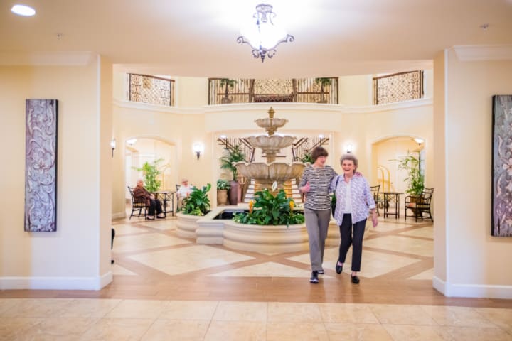 A spacious lobby with a central fountain and two people walking.