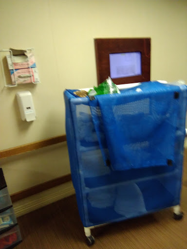 A blue utility cart filled with medical supplies in a hospital corridor.