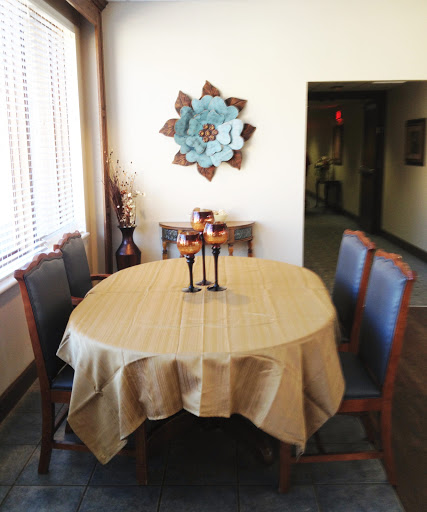 A cozy dining area featuring a round table adorned with a beige tablecloth, surrounded by stylish chairs and complemented by decorative wall art.