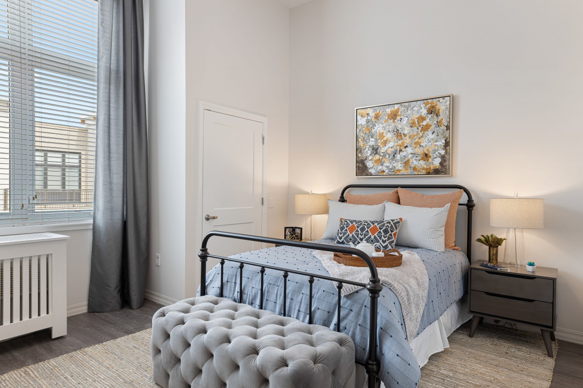 A modern bedroom featuring a metal bedframe, stylish decor, and a cozy atmosphere.