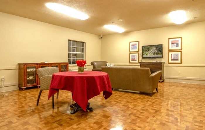 A cozy living room with a red tablecloth on the table, surrounded by comfortable sofas and wall decorations.