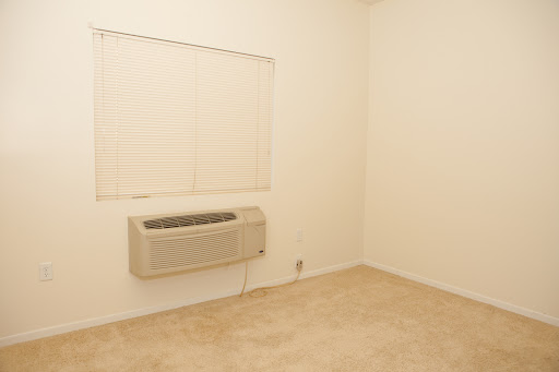An empty room featuring an air conditioning unit and blinds.