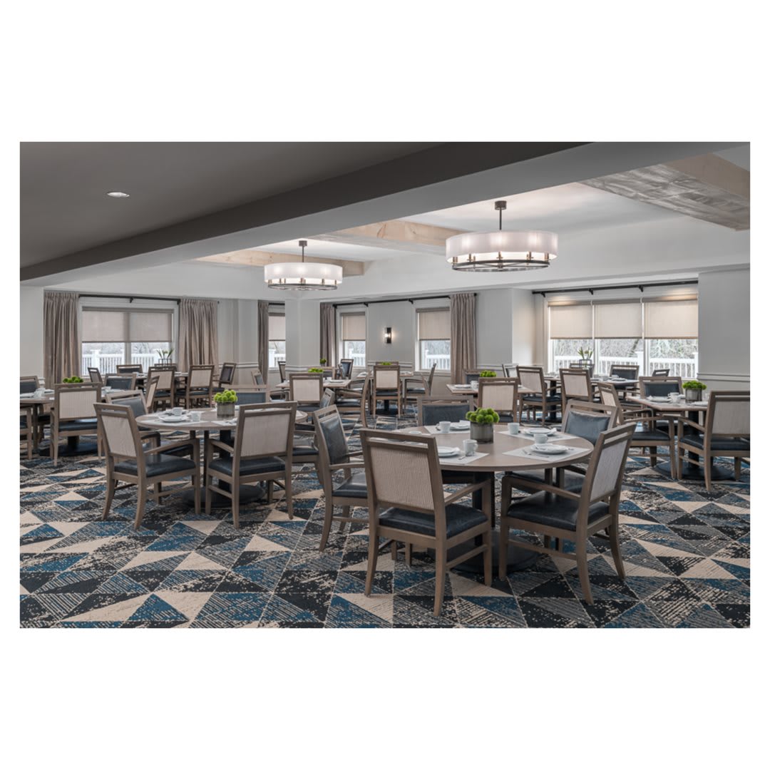 Spacious dining room with elegant chandeliers and neatly arranged tables and chairs.