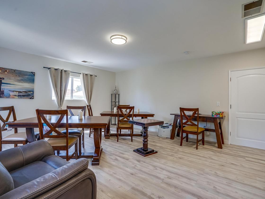 A spacious dining area with wooden tables and chairs, featuring bright lighting and hardwood flooring.