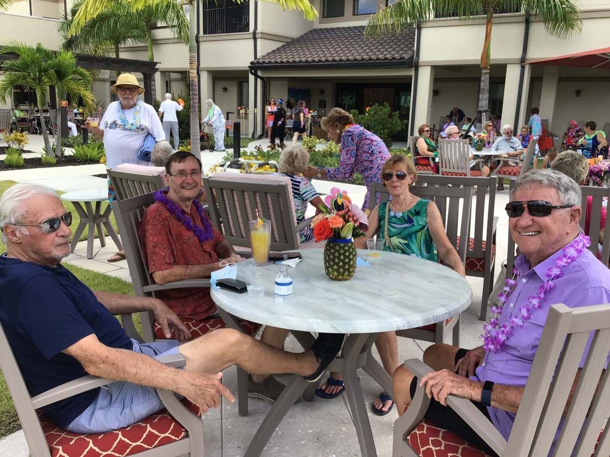 A group of friends relaxing by the pool in a tropical setting.