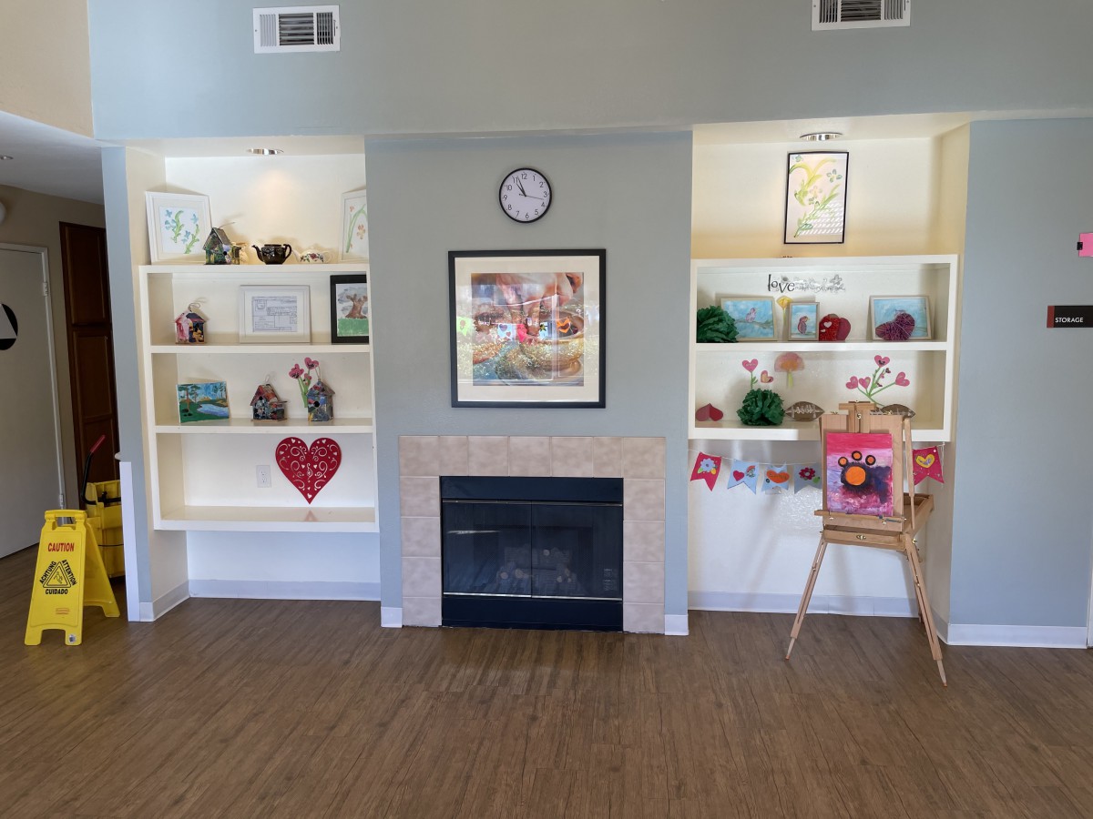 A cozy living room with a central fireplace, flanked by decorated shelves and a clock above.