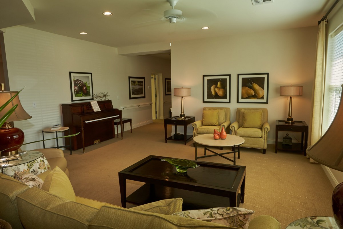 A cozy living room with a piano, comfortable seating, and artwork on the walls.