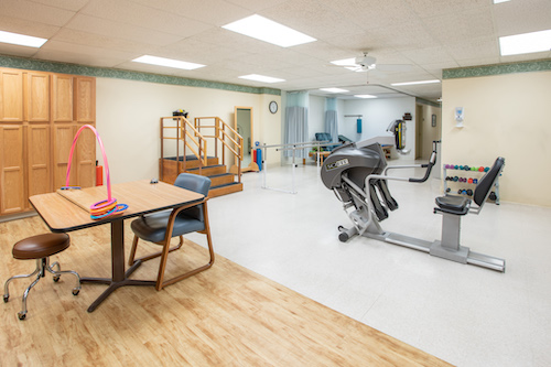 A spacious physical therapy room equipped with exercise machines and rehabilitation tools.