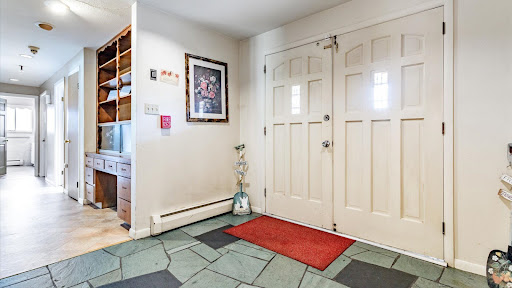 A welcoming entrance featuring a tiled floor, decorative wall art, and a bright double door.