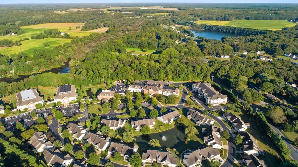 An aerial view of a suburban residential area surrounded by lush greenery and nearby lakes.