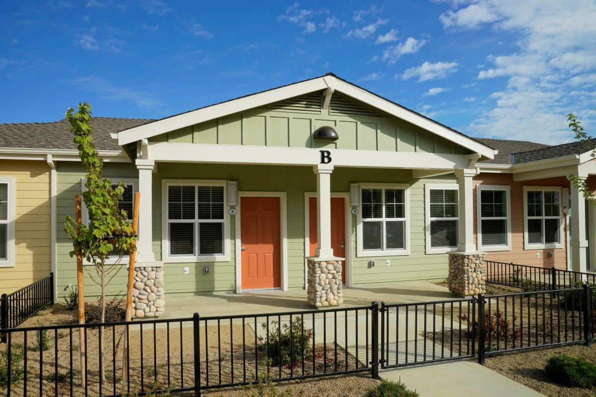A charming residential house with a porch and orange doors.