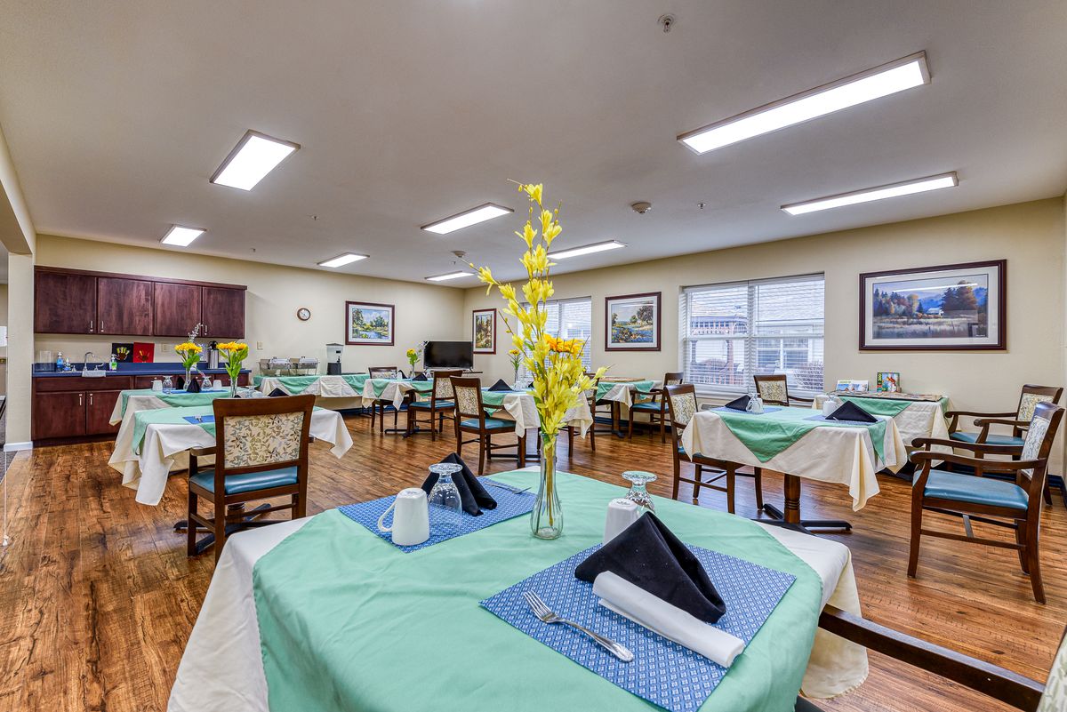 A well-decorated dining area with neatly set tables, featuring yellow flowers and folded napkins.