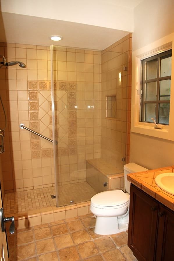 Modern bathroom with a glass-enclosed shower and tiled walls.