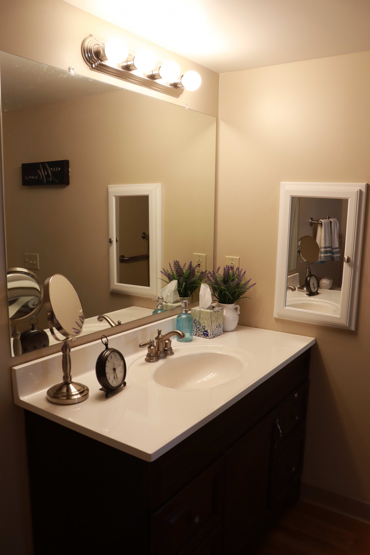 A neatly organized bathroom with a sink, mirror, and decorative items.
