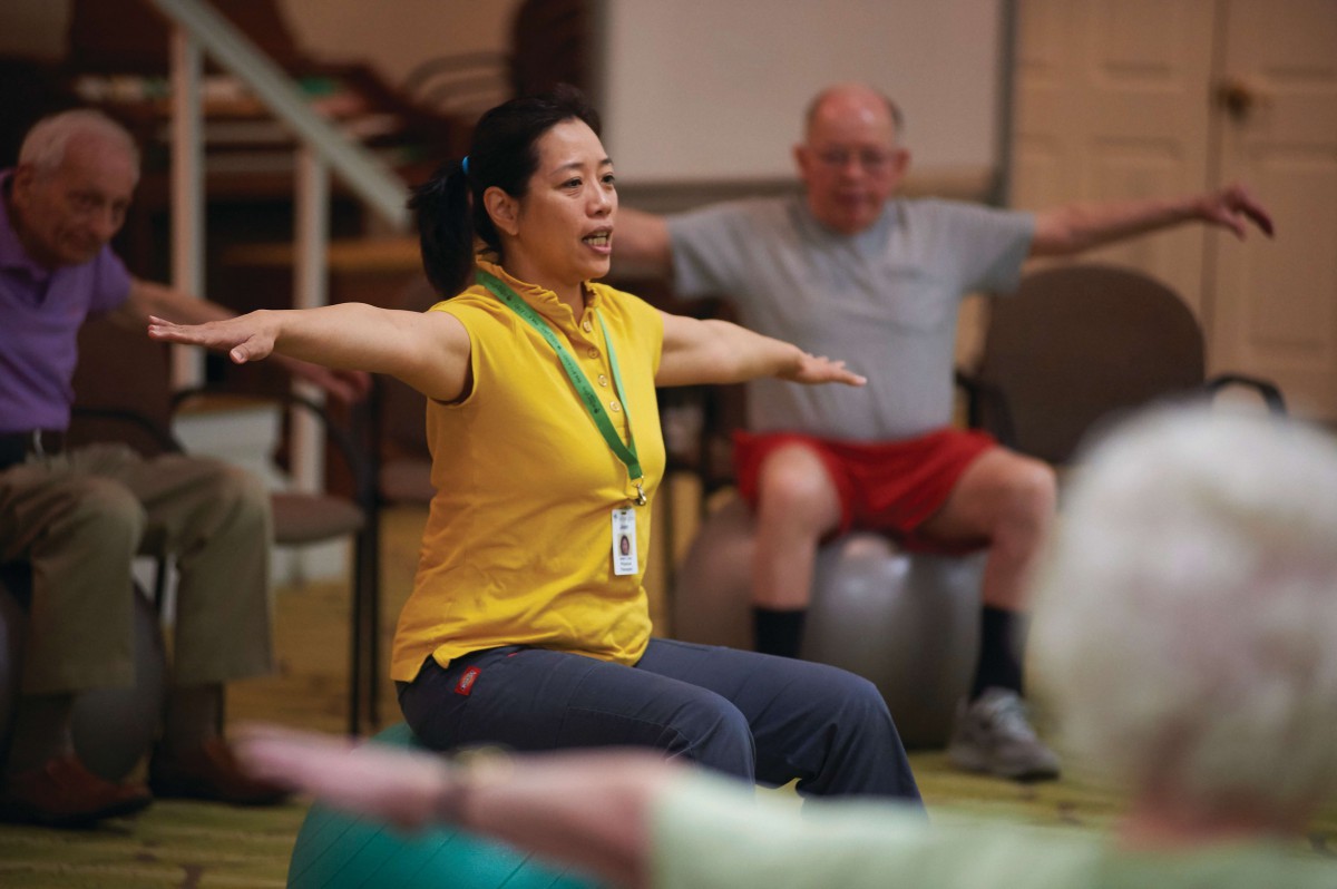 People participating in an indoor fitness class, with an instructor leading the session.