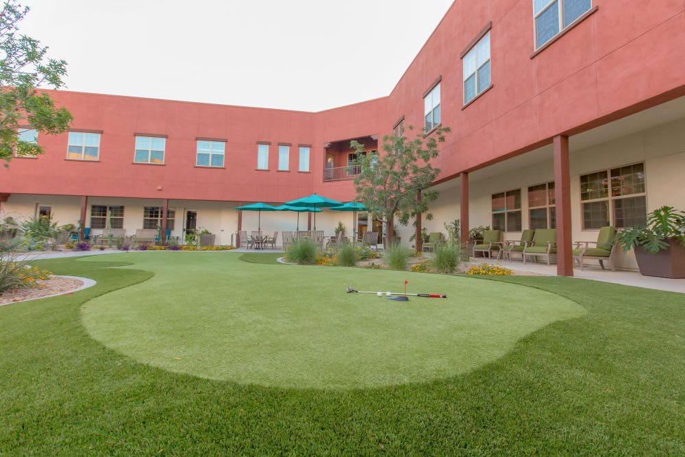 A courtyard with a green lawn surrounded by a red brick building.