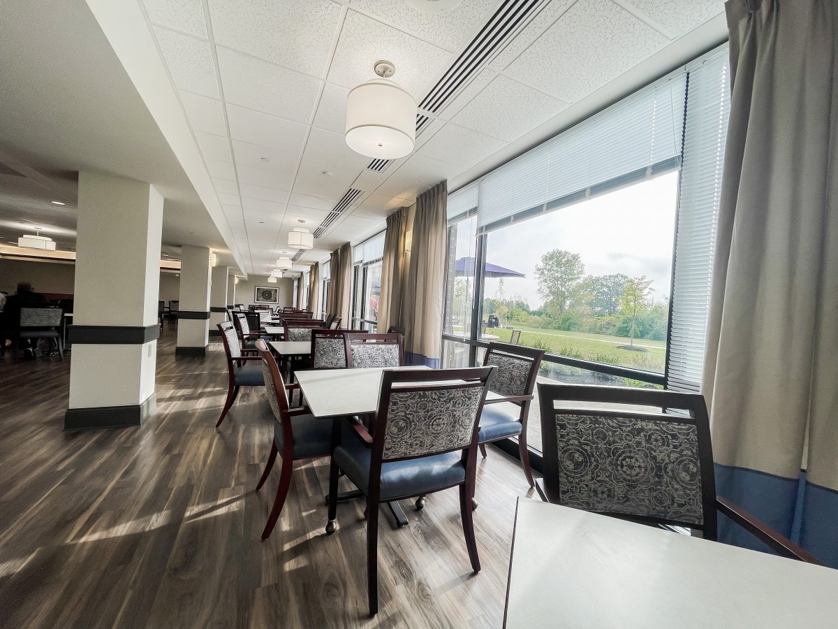 A modern dining area with large windows and neatly arranged tables and chairs.