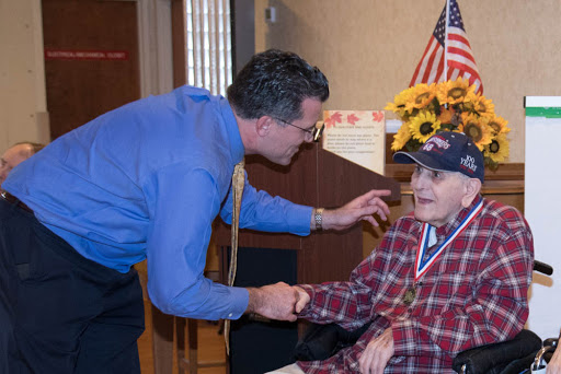 A heartfelt moment of connection between a veteran and a visitor during a community celebration.