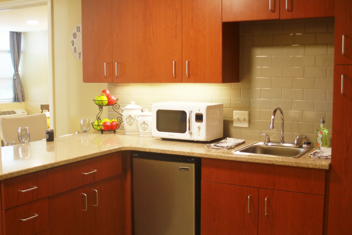 A cozy kitchen corner featuring a microwave, sink, and wooden cabinets.