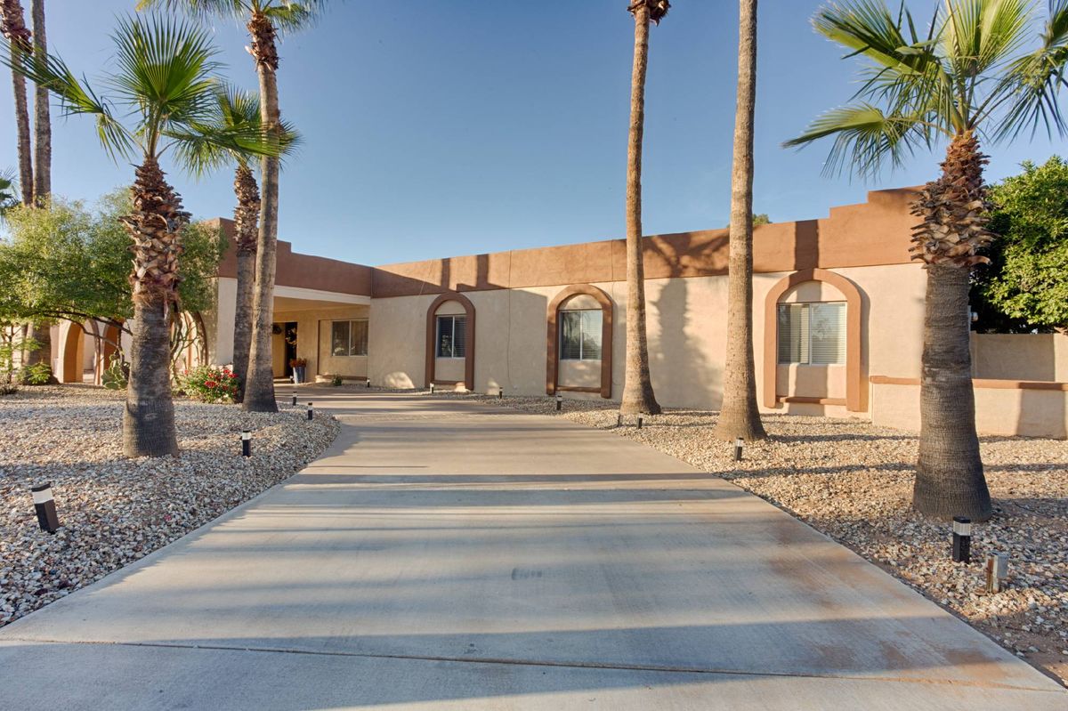 A modern desert home with palm trees and a spacious driveway.