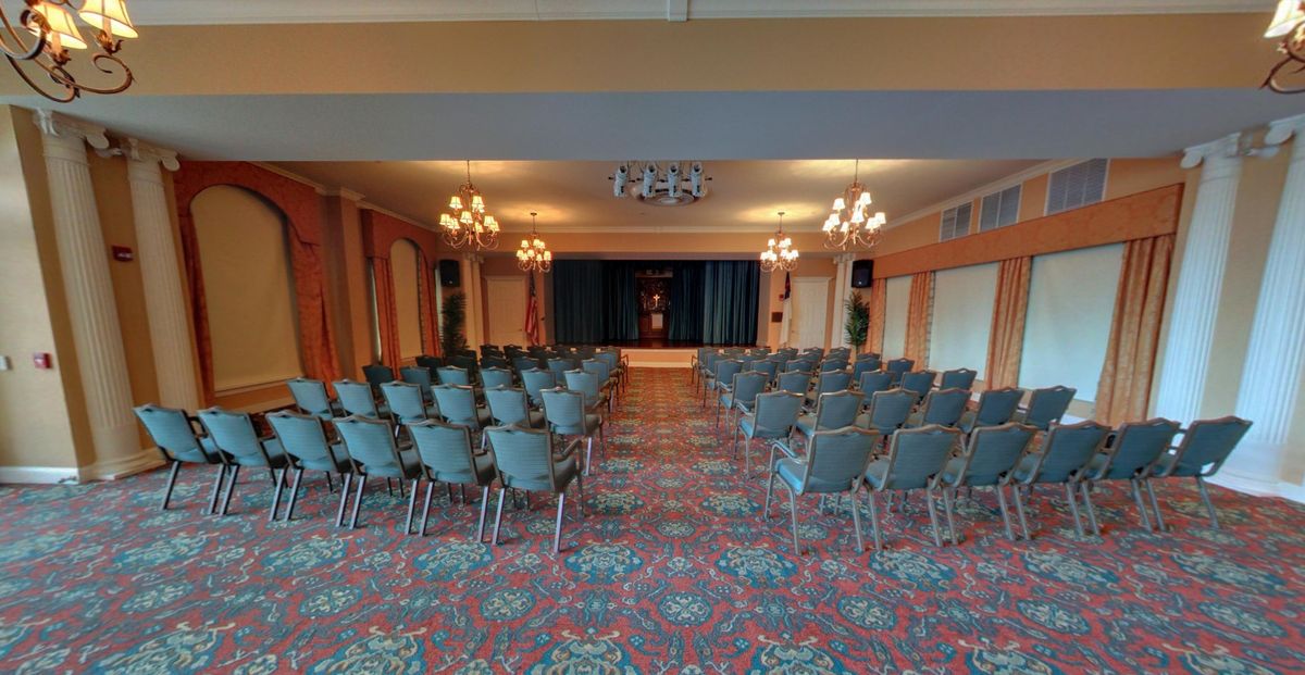 An empty conference room set up with rows of chairs facing a stage.