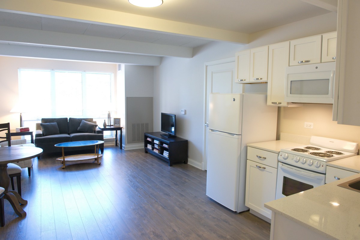 A modern open-space apartment with a kitchen, living area, and furniture.