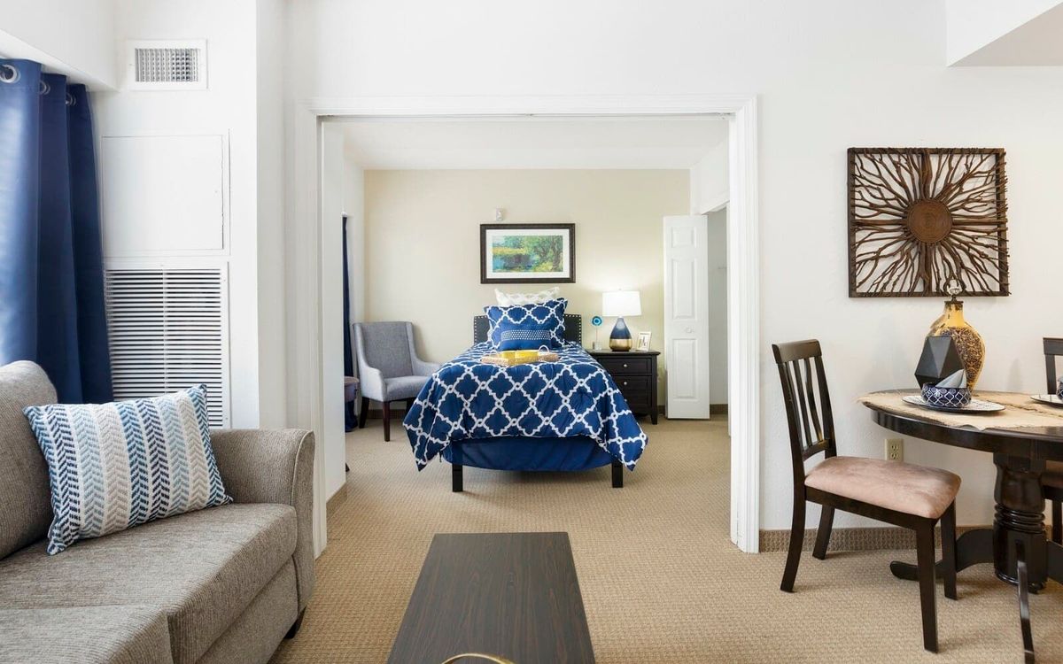 A cozy bedroom with a blue-patterned bedspread and comfortable furnishings.