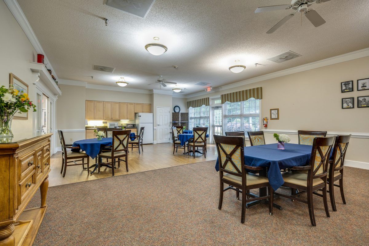 A spacious community dining area with tables and chairs, adjacent to a kitchen space.