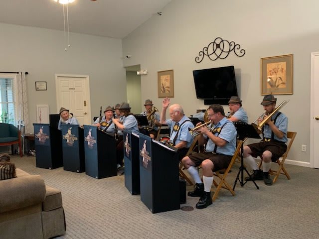 A band dressed in traditional attire performs indoors using brass instruments.
