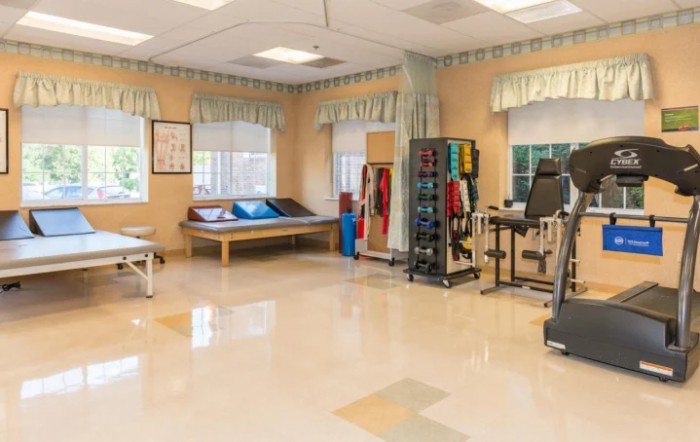 A spacious rehabilitation center equipped with various therapy tools and exercise machines.