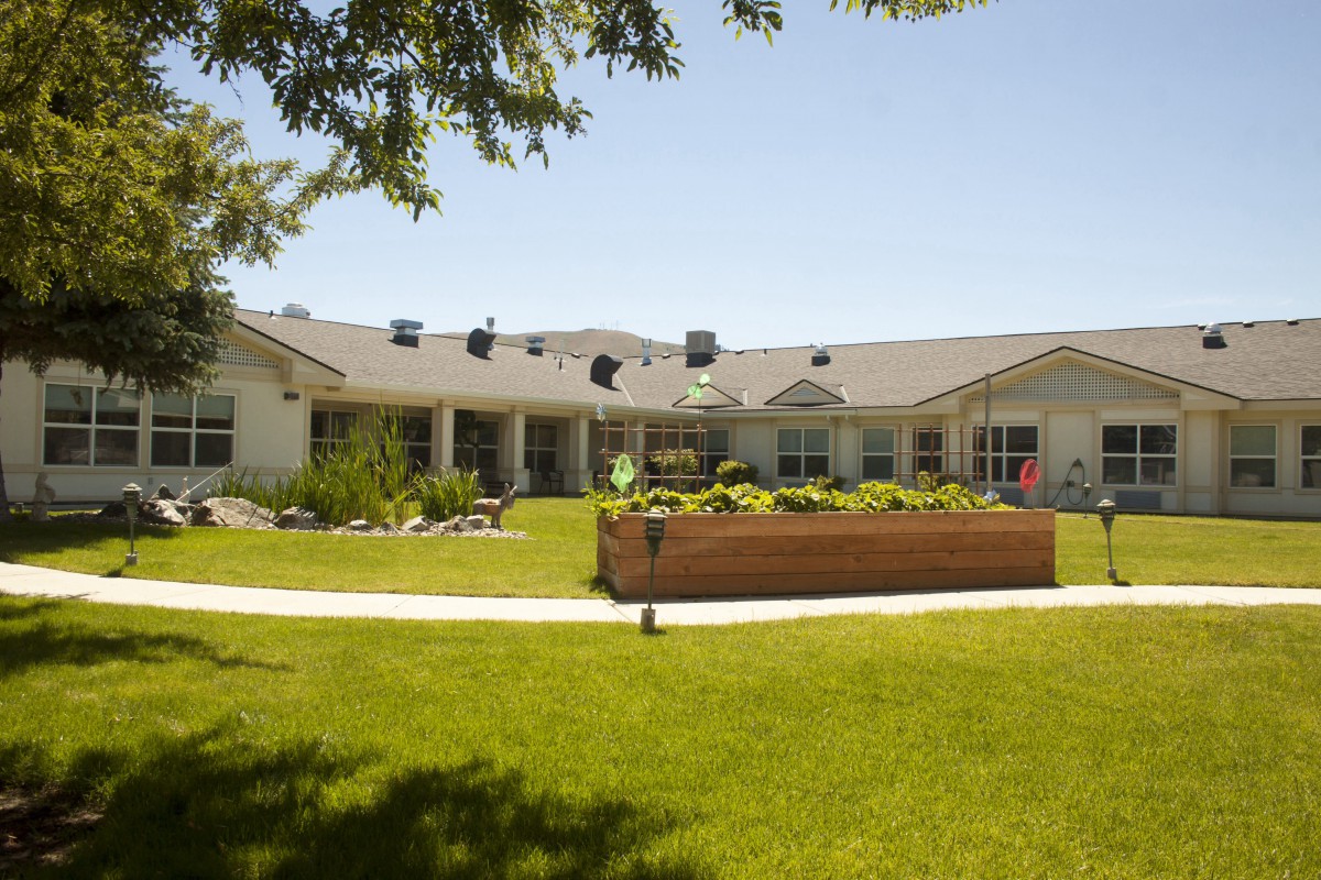 A sunny view of a building with a well-maintained lawn and garden.