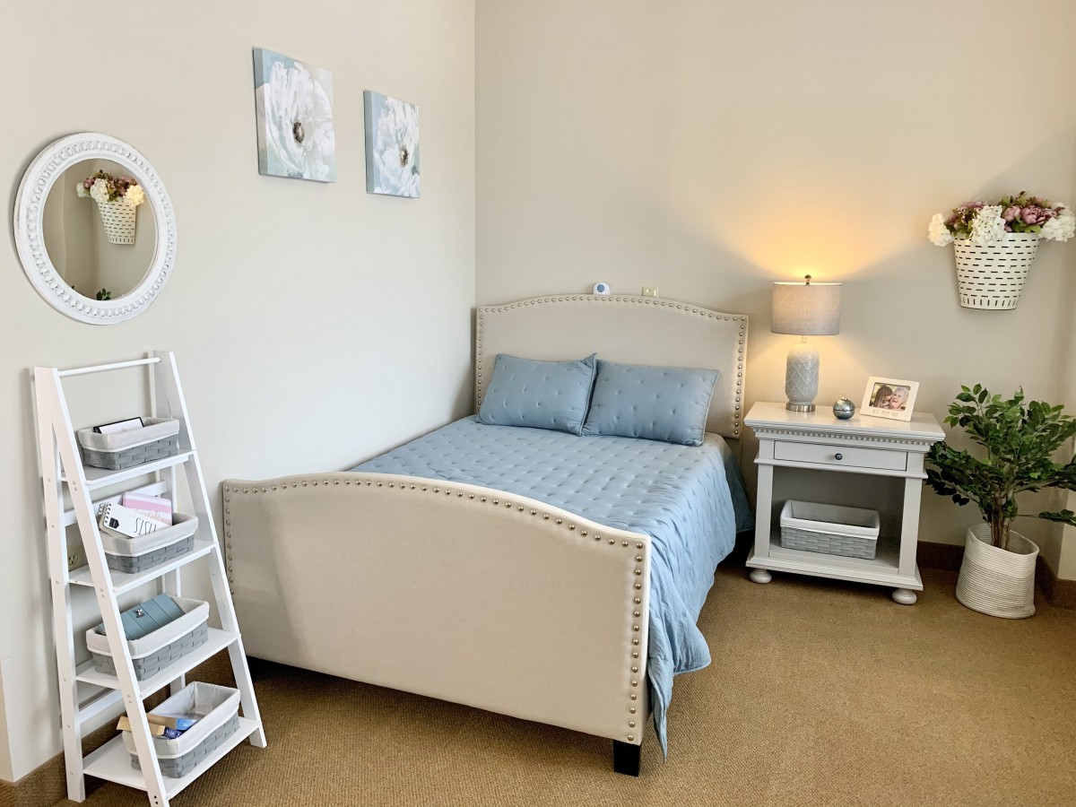 A cozy and modern bedroom with a neatly made bed, soft lighting from a lamp on the nightstand, and minimalist decor.